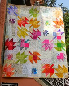 a colorful quilt hanging from the side of a building