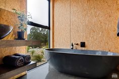 a large bathtub sitting next to a window in a room with wood paneling