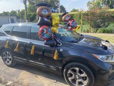 two large teddy bears sitting on top of a car with balloons in the shape of animals