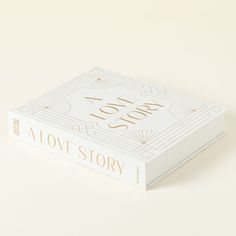 a love story book sitting on top of a white table next to a yellow wall