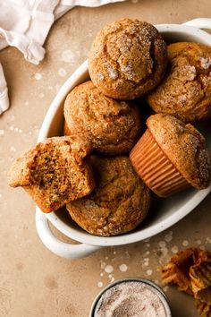 a bowl filled with muffins next to a cup of coffee