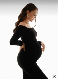 a pregnant woman in black is posing for the camera with her hands on her hips