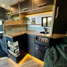 the interior of a camper with an oven, sink and storage compartment in it