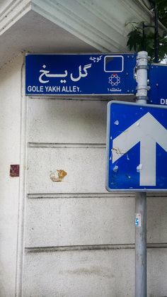 a blue street sign sitting on the side of a building next to a white wall