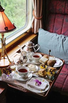 a tray filled with tea and pastries next to a window