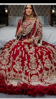 a woman in a red bridal gown sitting on a bed with her hands behind her head