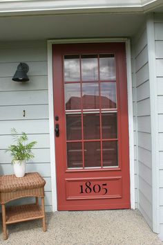 a red front door with a bench and potted plant