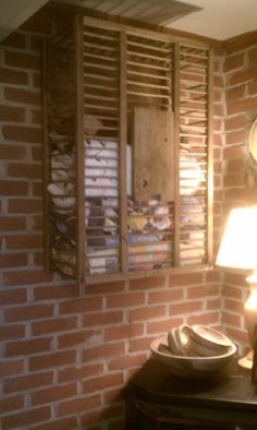 a room with a brick wall and wooden shutters on the window sill next to a lamp