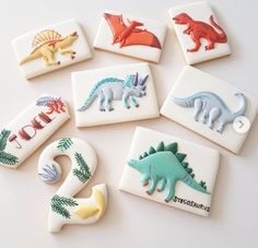 cookies decorated with different types of dinosaurs on white background, including one for the number two