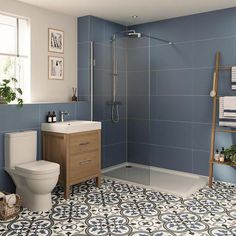 a bathroom with blue and white tiles on the floor, shower, toilet and sink