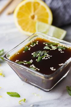 a square glass dish filled with sauce and garnished with herbs