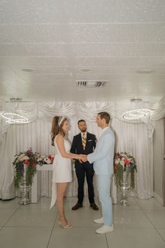 a man and woman standing in front of a white backdrop holding hands with each other