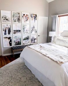 a white bed sitting in a bedroom next to a window with pictures on the wall