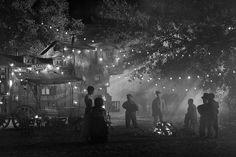 black and white photograph of people standing around in the dark