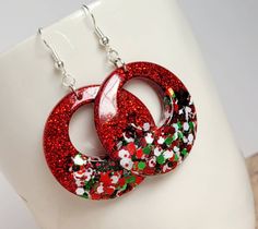 pair of red and green glittered earrings on white mannequin headdress