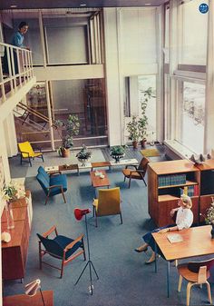 an old photo of a living room with chairs and bookshelves in the corner