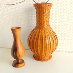 two vases sitting next to each other on a white counter top with a plant in it