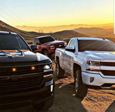 three pickup trucks parked in the desert at sunset