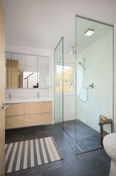 a bathroom with a shower, sink and toilet in the corner next to a striped rug