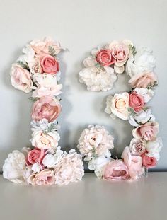 the letter e is made out of flowers and has pink, white, and peach blooms