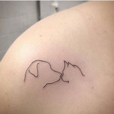 a woman's shoulder with a small tattoo of two cats kissing each other on it