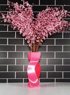 a vase with pink flowers in front of a brick wall