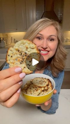 a woman holding up a bowl of food and a cracker in front of her face