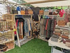 an outdoor market with lots of handbags and purses on display in the grass