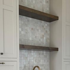 a kitchen with white cabinets and marble backsplash, gold faucet in the middle