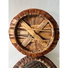 two wicker baskets sitting on top of each other in front of a white wall