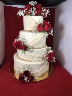 a three tiered wedding cake with red roses and baby's breath