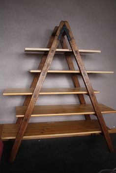 a wooden shelf with three shelves on each side and one shelf below it, in front of a gray wall