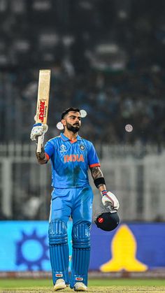 a man holding a cricket bat and ball in his hand while standing on the field