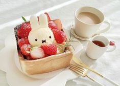 a plate with strawberries, strawberrys and a small bunny in it next to a cup of coffee