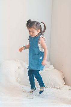 Yes! We have mini-sized aprons to help keep your kid’s clothes protected from all of their adventures indoors and outdoors. We created the apron to be quick and easy to put on a busy toddler. The lightweight and comfortable material makes it easy to convince your child to add another layer.  For more information on how Playful Bib For Playtime, Playful Blue Cotton Bib, Blue Cotton Bib For Playtime, Linen Products, Apron Design, Toddler Apron, Pinafore Apron, Shop Apron, Busy Toddler