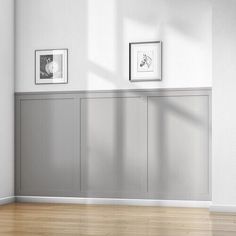 an empty room with two framed pictures on the wall and wood flooring in front of it