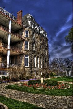 an old brick building with many windows and balconies on the second story, surrounded by flowers