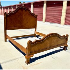 a wooden bed frame sitting on top of a parking lot next to a storage unit