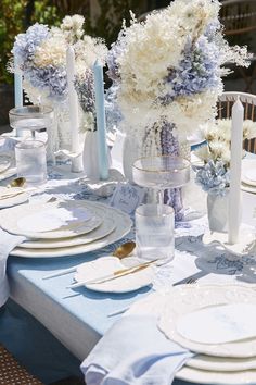 the table is set with white and blue flowers