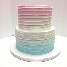 a multi layer cake with pink, blue and white frosting sitting on top of a plate