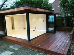 a wooden deck with glass doors on the top and bottom part, in front of a house