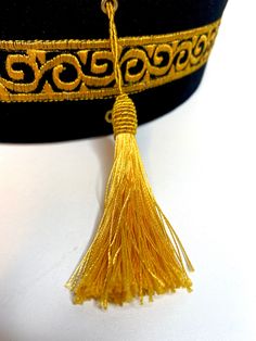 a gold tassel on top of a black hat