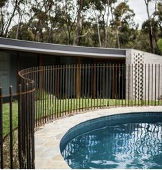 an outdoor swimming pool surrounded by trees and fenced in area next to a house