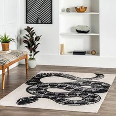 a living room with white walls and wooden flooring is decorated in black and white