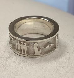 "This is a hieroglyphs ring that contains REAL raised hieroglyphs and not the 'fantasy/nonsensical' hieroglyphs which we are accustomed to seeing with many jewelers and websites. I am advanced amateur egyptologist (no accreditation), and can read and write hieroglyphs. The hieroglyphs in the band are an accurate representation of a Kingly formula offering, whch can be found on many stelas and tomb walls. The Hieroglyphic Inscription: 𓇓𓏏𓊵𓏙𓁹𓊨𓀭𓏃𓈖𓏏𓋀𓄿𓊹𓉼 \"nsw.t ḥtp dı͗ wsı͗r ḫnty-ı͗mnty.w nṯr ˁ3\" 'An offering which the king gives to Osiris, Foremost of Westerners, the great god'. Check out the Video!" Symbolic Wide Band Engraved Rings, Symbolic Engraved Wide Band Ring, Symbolic White Gold Engraved Ring, Read And Write, Star Ring, Ring Band, Rings Statement, Band Rings, Statement Rings