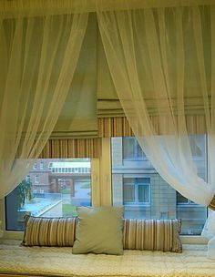 a window with sheer curtains and pillows on it