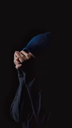 a person holding their hands together in the dark, with one hand on his chest