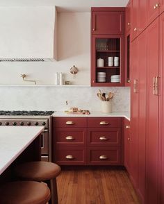 a kitchen with red cabinets and white counter tops