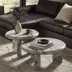 two tables sitting next to each other in front of a couch and coffee table with books on it