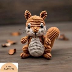 a small crocheted squirrel sitting on top of a wooden table next to nuts